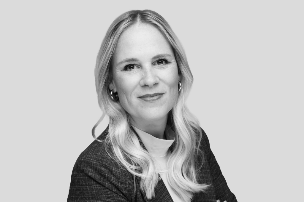 Schwarz-weiß Porträt einer Frau mit langen, gewellten, blonden Haaren und Business-Outfit.